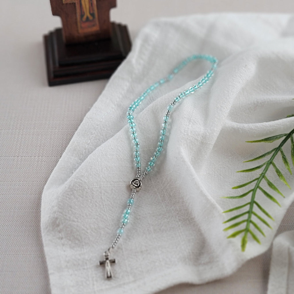 Bluebell rosary on cloth at base of crucifix photographed at an angle
